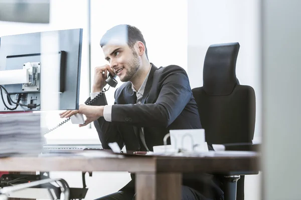 Επιχειρηματίας Κάθεται Στο Γραφείο Τον Υπολογιστή Και Γραφειοκρατία Χρησιμοποιώντας Smartphone — Φωτογραφία Αρχείου
