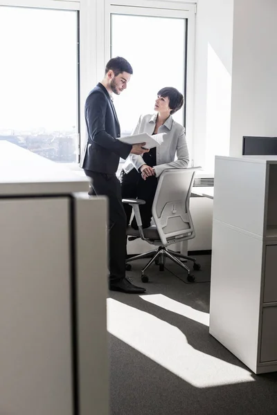 Businesspeople standing in office looking at paperwork