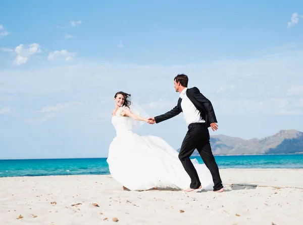 新娘和新郎沿着海滩奔跑 — 图库照片