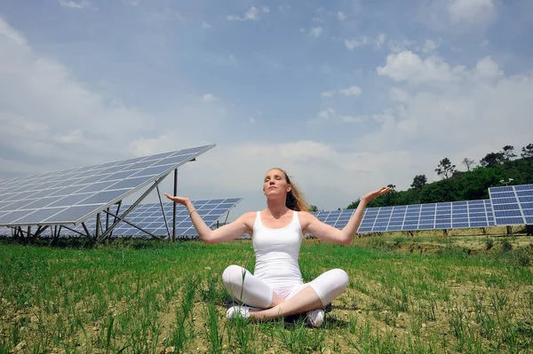 woman doing yoga in front of solar panel