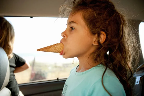 Young girl with ice cream cone in mouth