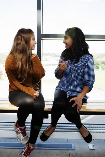 Duas Alunas Adolescentes Sentadas Conversando Corredor — Fotografia de Stock