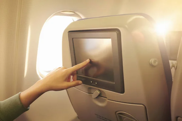 Close up of female hand using touchscreen in airplane headrest