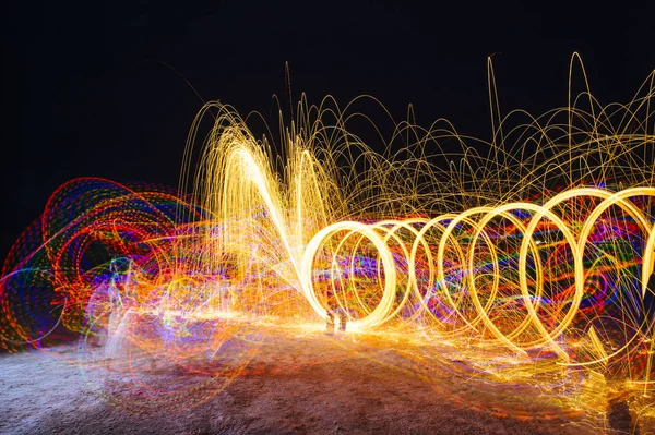夜に輝く黄色の円形の光の道を作成する女性 — ストック写真