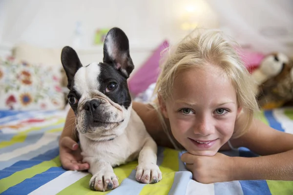 女の子の肖像画とかわいい犬がベッドの上に横たわって — ストック写真