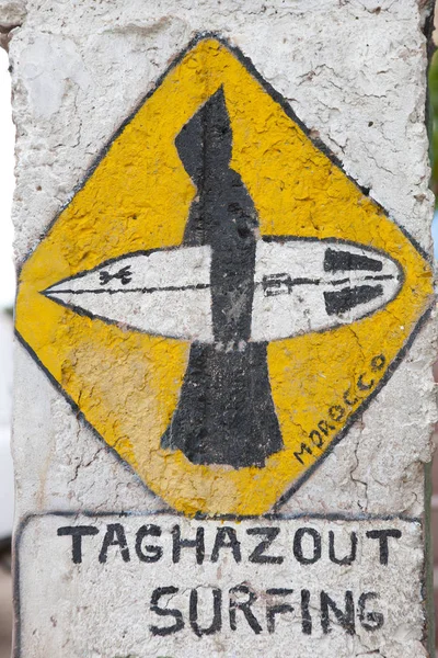 Painted sign of surfer in traditional clothing with a surfboard, Taghazout, Morocco