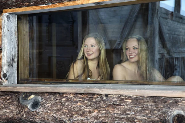 Two Young Women Looking Out Log Cabin Sauna Window — Stock Photo, Image