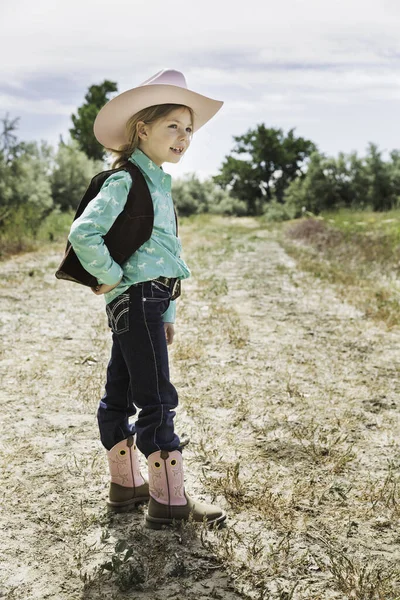 Girl wearing cowboy hat and boots on path