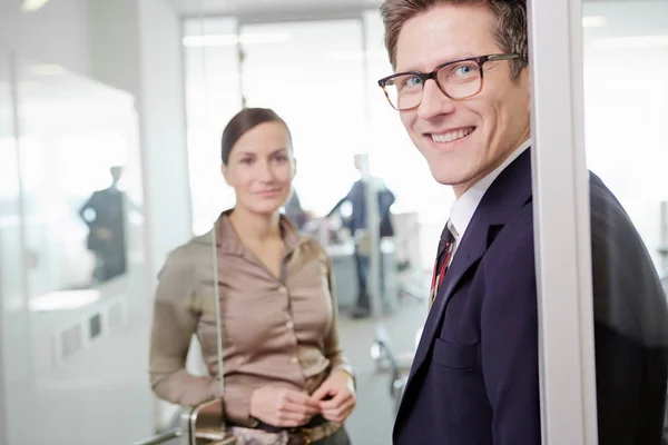 Man and woman wearing business attire standing in door frame of office