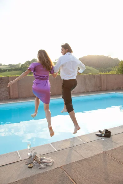 couple jumping into pool,dressed