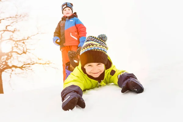 Pojke Liggande Snö Med Vän Bakgrunden — Stockfoto