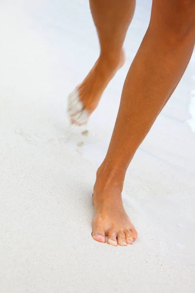女人在白沙滩上奔跑的脚 — 图库照片