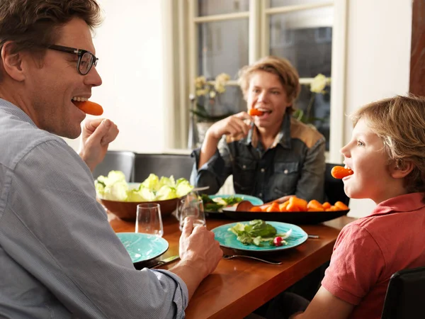 Father and sons sitting at table with healthy meal