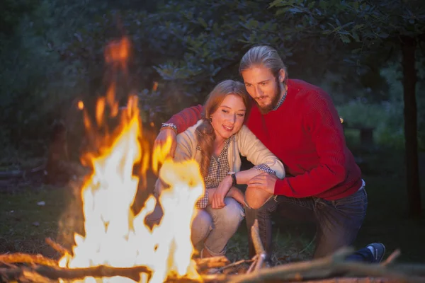 Couple watching camp fire burn