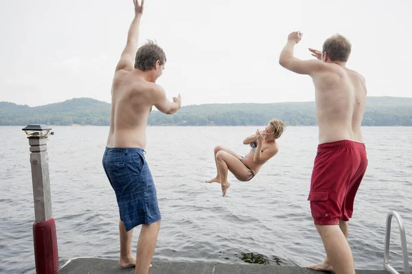 Mężczyźni Wyrzucający Młodą Kobietę Pomostu Jeziora — Zdjęcie stockowe