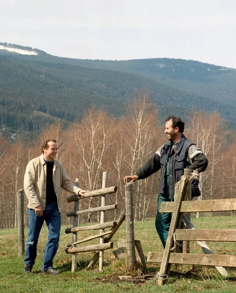 Two men talking over fence and gate