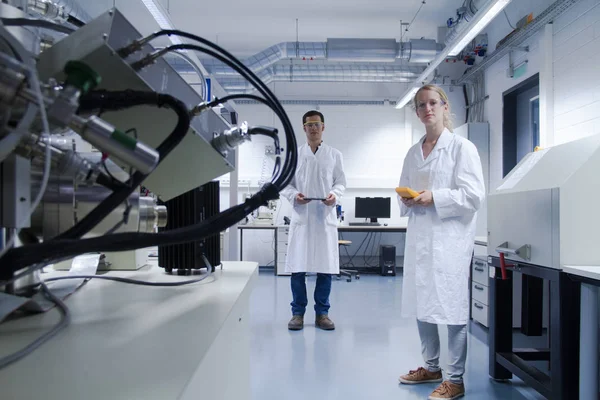 Δύο Επιστήμονες Που Φορούν Εργαστηριακές Ποδιές Και Γυαλιά Ασφαλείας Στέκονται — Φωτογραφία Αρχείου