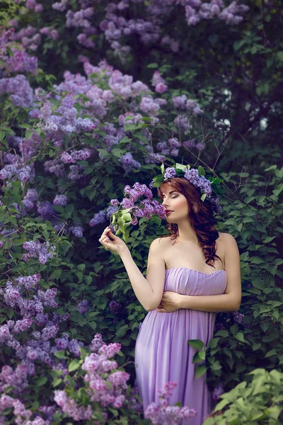 Uzun Menekşe Elbiseli Güzel Bir Kadın Kafasında Çiçekler Ellerinde Leylak — Stok fotoğraf