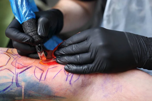 tatoo drawing on his shoulder. tattoo,tattoo artist does the tattoo on the man\'s hand.