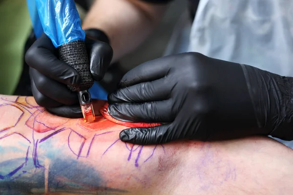 tatoo drawing on his shoulder. tattoo,tattoo artist does the tattoo on the man\'s hand.