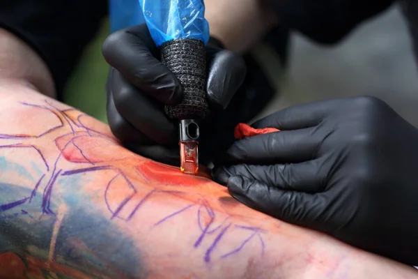 tatoo drawing on his shoulder. tattoo,tattoo artist does the tattoo on the man's hand.