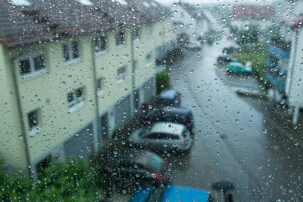 通りや家を見下ろす窓に雨が降り — ストック写真