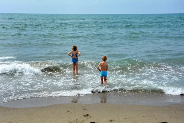 파란색 수영복을 소녀는 해변에서 물위에 바다를 바라본다 — 스톡 사진