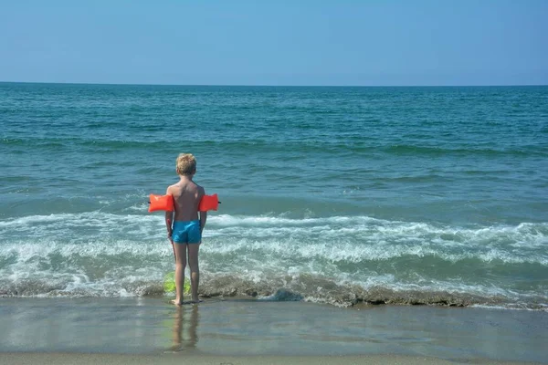 Маленький Мальчик Красными Купальниками Стоит Пляже Смотрит Море — стоковое фото