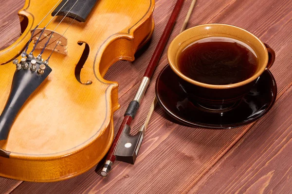 Violin and cup of coffee on a wooden background.