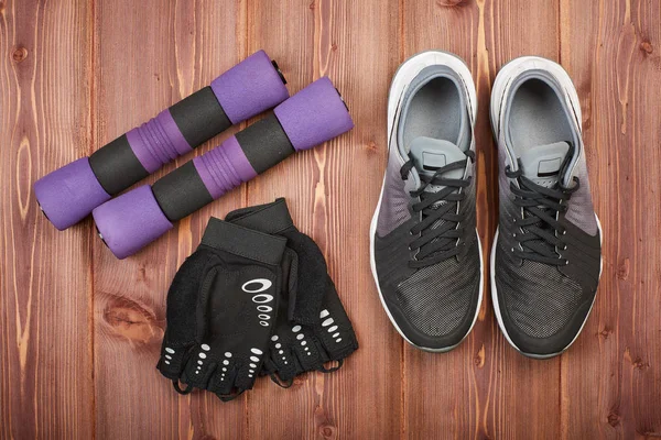 Dumbbells, sneakers and sport accessories on a wooden floor. Top view. Fitness, sport and healthy lifestyle concept.