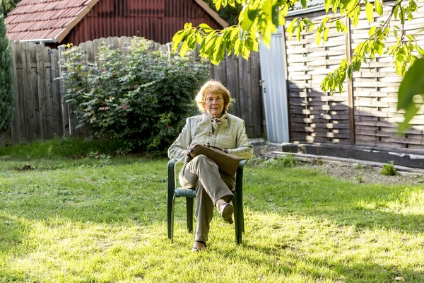 Пожилая Женщина Сидит Пластиковом Кресле Своем Саду Наслаждается Солнцем — стоковое фото