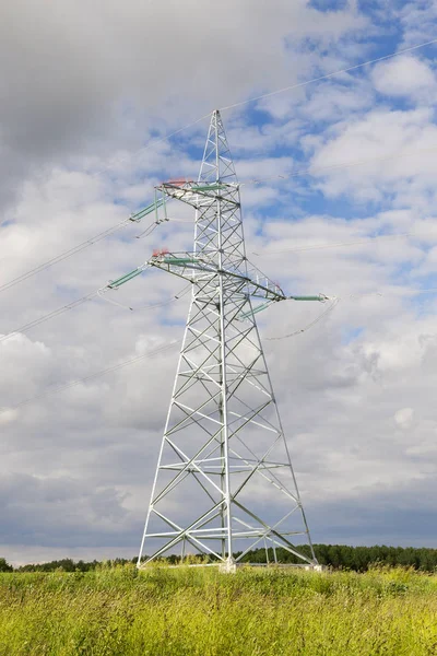 metal poles for electrical lines in the field. Photo close-up in summer. Focus on the pole. In the background the sky with clouds