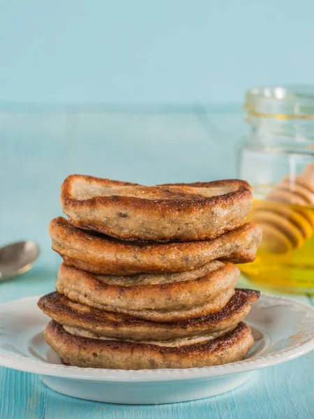 Stack of small pancakes with banana and chia seeds on light blue background. Pancake with chia or poppy seeds.
