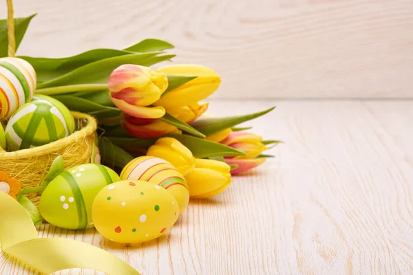 Kolorowe Pisanki Koszyku Wiosenne Tulipany Wstążka Drewnianym Tle Karta Okolicznościowa — Zdjęcie stockowe