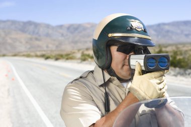 Mature traffic officer monitoring speed through radar gun clipart