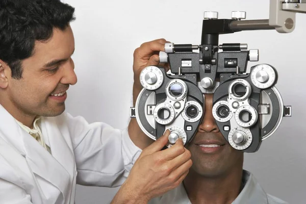 Reifer Männlicher Optometrist Stellt Phoropter Panels Ein Während Patient Untersucht — Stockfoto