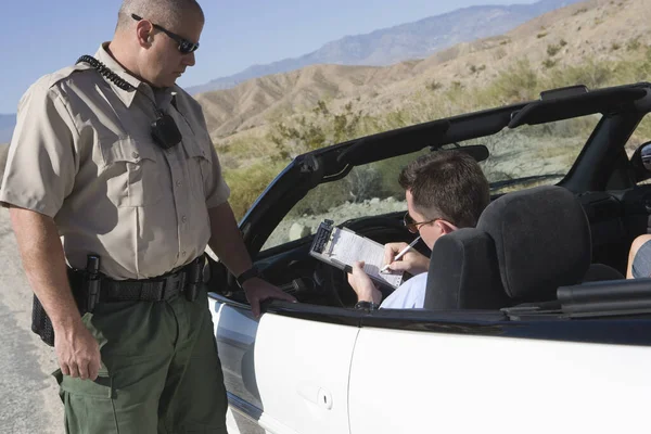 車で立っている交通警官とチケットに書いている中年の男 — ストック写真