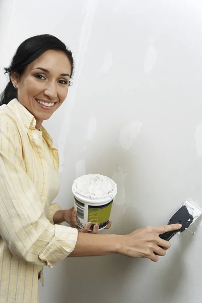 快乐女人在墙上涂油灰的画像 — 图库照片