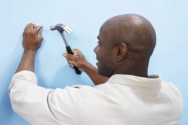 Glücklicher Afroamerikaner Hämmert Nagel Blaue Wand — Stockfoto