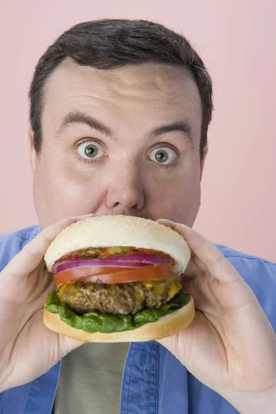 Ritratto Uomo Mezza Età Che Mangia Hamburger Sfondo Rosa — Foto Stock