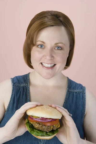 Portret Szczęśliwej Kobiety Średnim Wieku Trzymającej Hamburgera Kolorowym Tle — Zdjęcie stockowe