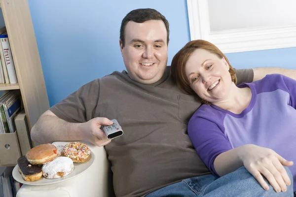 Happy obese couple watching television at home