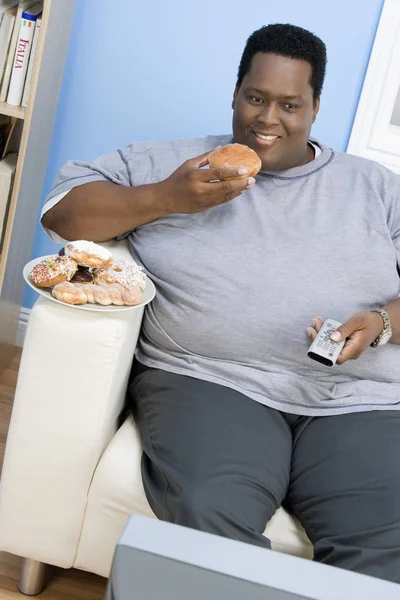 Ein Afroamerikanischer Mann Isst Donut Während Fernsieht — Stockfoto