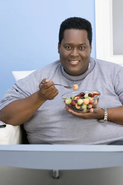 Uomo Afroamericano Obeso Che Guarda Televisione Mentre Mangia Frutta Casa — Foto Stock