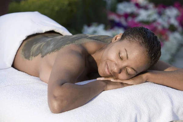 Una Mujer Feliz Afroamericana Acostada Una Cama Masaje Con Paquete — Foto de Stock