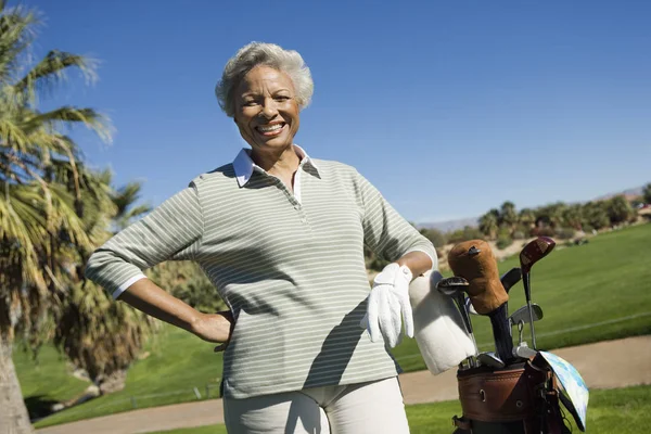 Portrait of happy senior African American woman with golf bag at golf course