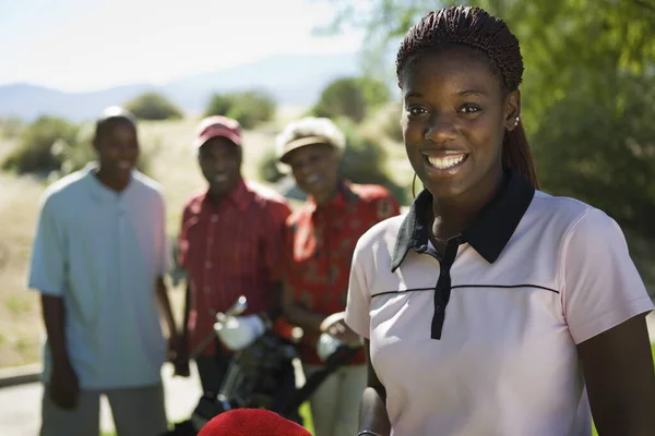 与有背景的人一起参加高尔夫球场的快乐的非洲裔美国妇女的画像 — 图库照片