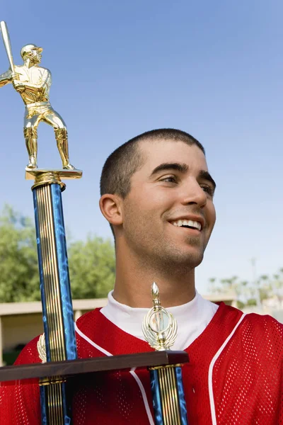 Happy young male player holding baseball trophy