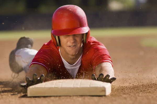 Young baseball player sliding towards second base on field