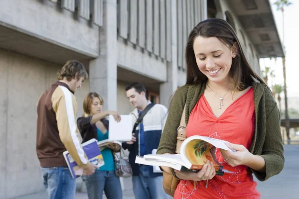 Giovane Studentessa Lettura Libro Con Gli Amici Background Campus — Foto Stock
